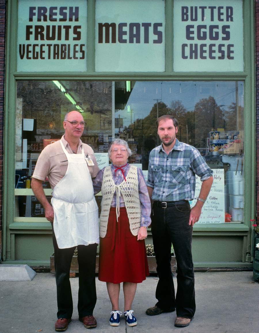 A 3-generation family of small business owners standing in front of their grocery store, 1970s or 1980s, USA.