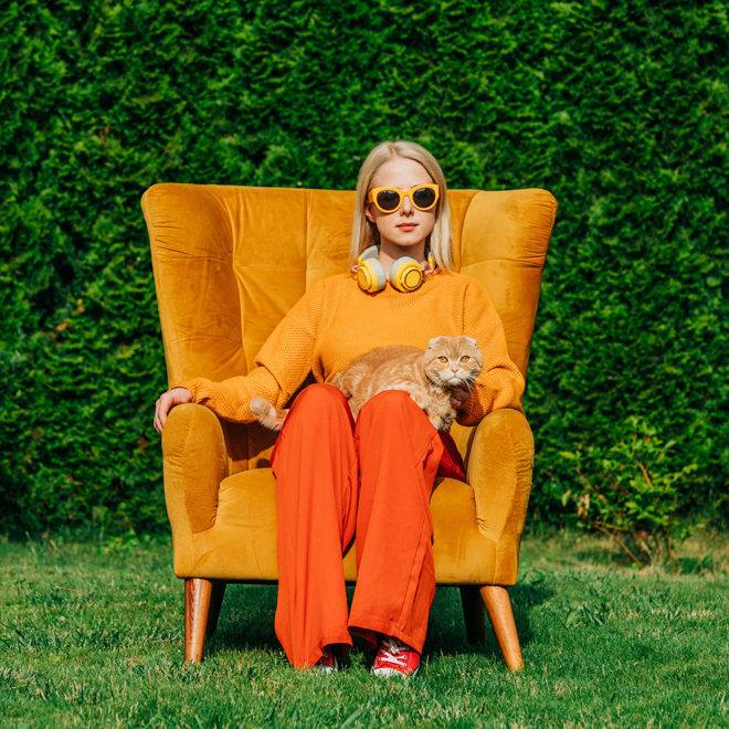 Blond woman wearing sunglasses sitting on chair with cat