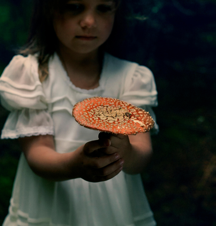 Caucasian girl holding mushroom in forest